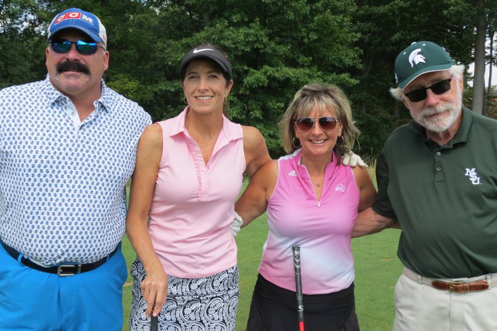Four people on course smiling
